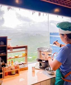 una mujer está preparando comida en una cocina en Giăng's House Farmstay & Glamping en Bao Loc