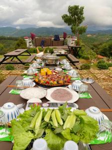 una mesa larga con platos de comida. en Giăng's House Farmstay & Glamping en Bao Loc