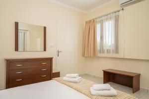 una camera con letto, cassettiera e specchio di MAKIS VILLAGE-APARTMENTS a Ayia Evfimia
