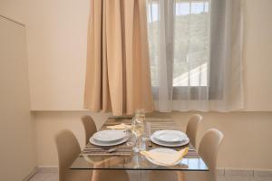 un tavolo da pranzo con sedie e una finestra di MAKIS VILLAGE-APARTMENTS a Ayia Evfimia
