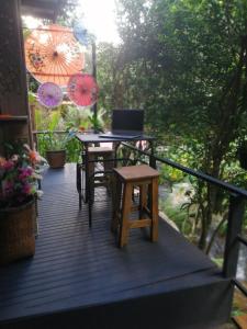 a wooden deck with a table and chairs and umbrellas at แม่อุ๊ยโฮมสเตย์&mae uai homestay in Ban Pok Nai
