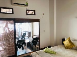 a bedroom with a bed and a balcony with a table and chairs at Hikka Beach Flat in Hikkaduwa