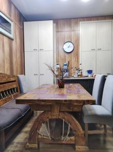 ein Esszimmer mit einem Holztisch und einer Uhr an der Wand in der Unterkunft Резидент in Dnipro