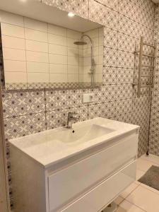 uma casa de banho com um lavatório branco e um espelho. em City Park Apartment em Vilnius
