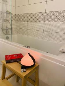 a lamp on a table next to a bath tub at City Park Apartment in Vilnius