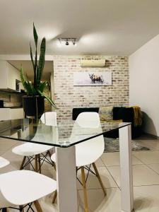 a dining room with a glass table and white chairs at Urban Retreat with a View in Windhoek