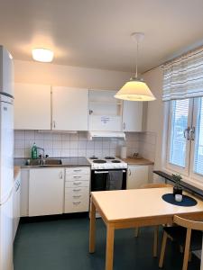 cocina con armarios blancos y mesa de madera en RS Lägenhetshotell Skövde en Skövde