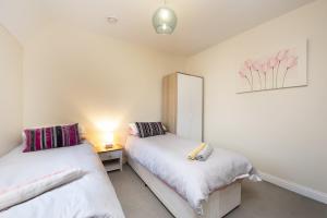 a bedroom with two beds and a lamp on a table at Inaras place in Aylesbury