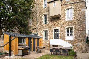 einen Hinterhof mit einem Gebäude mit einem Tisch und Stühlen in der Unterkunft Force 9 - Proche plage de Rochebonne in Saint-Malo