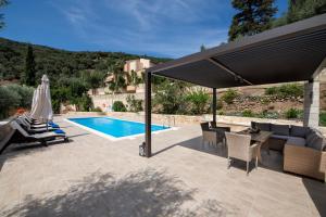 a patio with a pool and a black umbrella at Serenity River Villa in Palaiochora