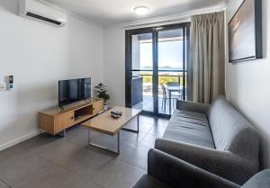 uma sala de estar com um sofá, uma televisão e uma mesa em WhitsunStays - The Regal (2br/2bth, Central) em Mackay