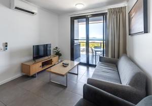 Una sala de estar con un sofá, un televisor y una mesa. en WhitsunStays - The Regal (2br/2bth, Central), en Mackay