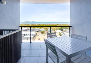 una mesa y sillas en un balcón con vistas al océano en WhitsunStays - The Regal (2br/2bth, Central), en Mackay