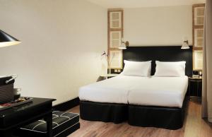 a hotel room with a large bed and a desk at Boutique Hotel H10 Catalunya Plaza in Barcelona