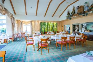 un restaurante con mesas blancas y sillas rojas en Ferien Hotel Spree-Neisse, en Neuhausen