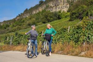 un hombre y una mujer de pie con bicicletas en un camino en Weingut-Ferienwohnung Heinz Dostert, en Nittel