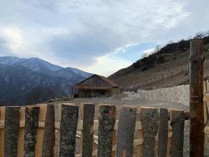 una valla de madera frente a un edificio con montañas en Hovk Farms en Dilijan