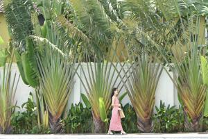 Eine Frau in einem Kleid, die durch einen Garten geht. in der Unterkunft Shining Riverside Hoi An Boutique & Spa in Hoi An