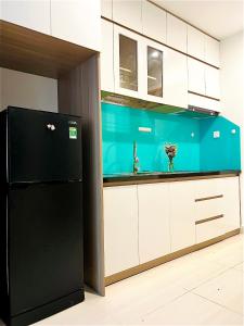 einen schwarzen Kühlschrank in einer Küche mit weißen Schränken in der Unterkunft Vin Grand Park - TP. Thủ Đức in Tân Vạn