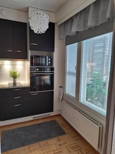a kitchen with black cabinets and a large window at Saunallinen yksiö in Pieksamaki