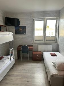 1 dormitorio con 2 camas, escritorio y ventana en Hostel Radom, en Radom