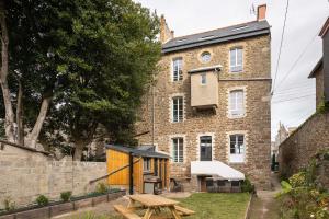 ein altes Backsteingebäude mit einem Picknicktisch davor in der Unterkunft Le Cargo - A 300m de la plage de Rochebonne in Saint-Malo