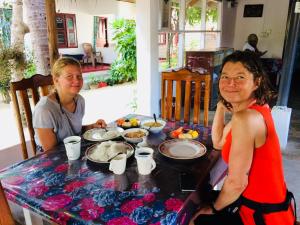 Due donne sedute a un tavolo con cibo di Tropicana Home Stay ad Arugam