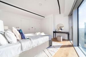 a white bedroom with a large bed and a mirror at Fantastic immense 1 BR flat, Battersea Power St in London