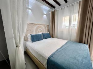 a bedroom with a bed with blue pillows and a window at Mare Apartments Marbella in Marbella
