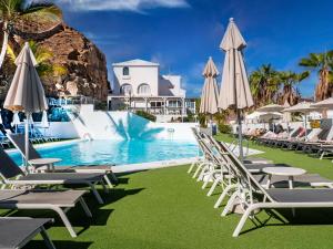 a pool with chaise lounge chairs and umbrellas at Canaima Sea View/Terrace/Pool in Mogán