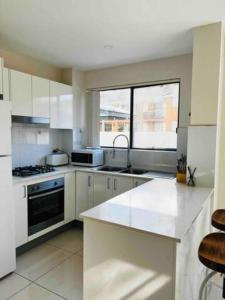 a kitchen with white cabinets and a large window at 2Bedrooms 2Bathrooms Oasis in Parramatta w parking in Sydney