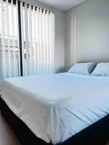 a white bed in a bedroom with a window at 2Bedrooms 2Bathrooms Oasis in Parramatta w parking in Sydney