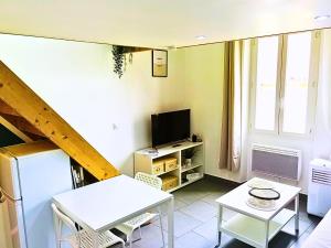 a living room with a white table and a television at Le Cocon in Toulon