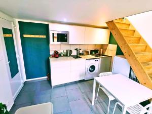 cocina con armarios blancos, mesa y lavadora en Le Cocon, en Toulon
