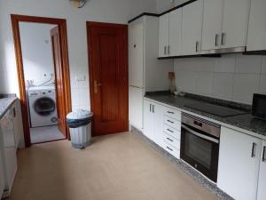 cocina con armarios blancos, lavadora y secadora en Casa Margarida, en Allariz