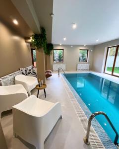 a pool in a hotel room with white furniture and a swimming pool at Casa Forrest & SPA in Muntele Săcelului