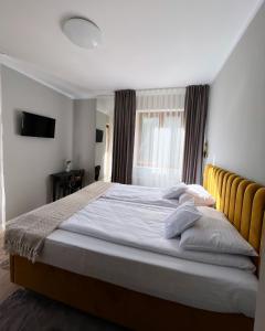 a bedroom with a large bed with white sheets at Casa Forrest & SPA in Muntele Săcelului