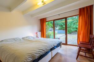 um quarto com uma cama e uma grande janela em Au Ptit Bois Charmant em La-Roche-en-Ardenne