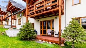 une maison dotée d'une terrasse couverte en bois avec une chaise. dans l'établissement Wonder Home - Domek Karkonosz z kominkiem i dwoma sypialniami - tuż przy stoku Myśliwska 42-1, à Karpacz 11 autres photos
