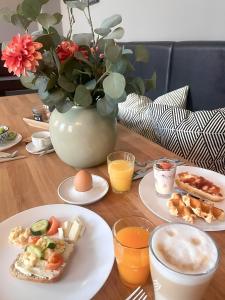 einen Tisch mit Teller mit Lebensmitteln und eine Vase mit Blumen in der Unterkunft Apartment Hotel Lindeneck in Erfurt