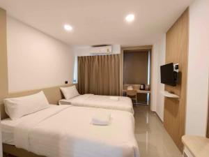 um quarto de hotel com duas camas e uma televisão em SNOW HOUSE Buriram em Buri Ram