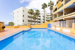 a swimming pool in front of a building at Playa La Arena with pool and privat parking in Puerto de Santiago