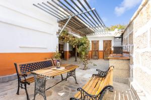 patio z 2 ławkami i drewnianym stołem w obiekcie Casa Argelia w mieście Vilaflor