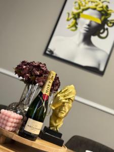 a bottle of champagne and a vase of flowers on a table at Svatého Pasáž BOUTIQUE Apartments with free parking in Trnava