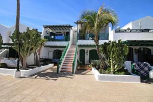 a white house with palm trees in front of it at Nautic Apartment in Puerto del Carmen in Tías