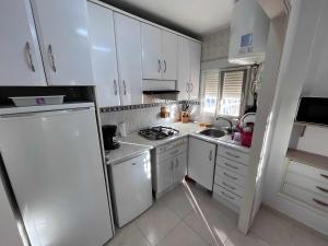 cocina con armarios blancos y nevera blanca en Apartamento con terraza en San Juan Playa, en Alicante
