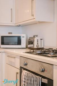 een keuken met een magnetron en een fornuis top oven bij The Flat 2 by Sheryl - Stone throw to Northampton Gen Hosp & Town Centre in Northampton