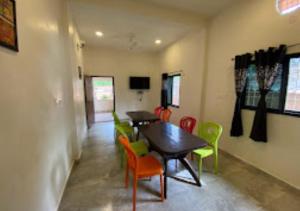 a dining room with two tables and colorful chairs at Erisha Tadoba Chandrapur in Mohurli