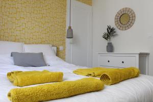 un letto bianco con due asciugamani gialli sopra di Bienvenue chez Ed a Villeurbanne
