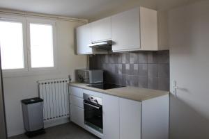 una piccola cucina con armadi bianchi e una finestra di Bienvenue chez Ed a Villeurbanne